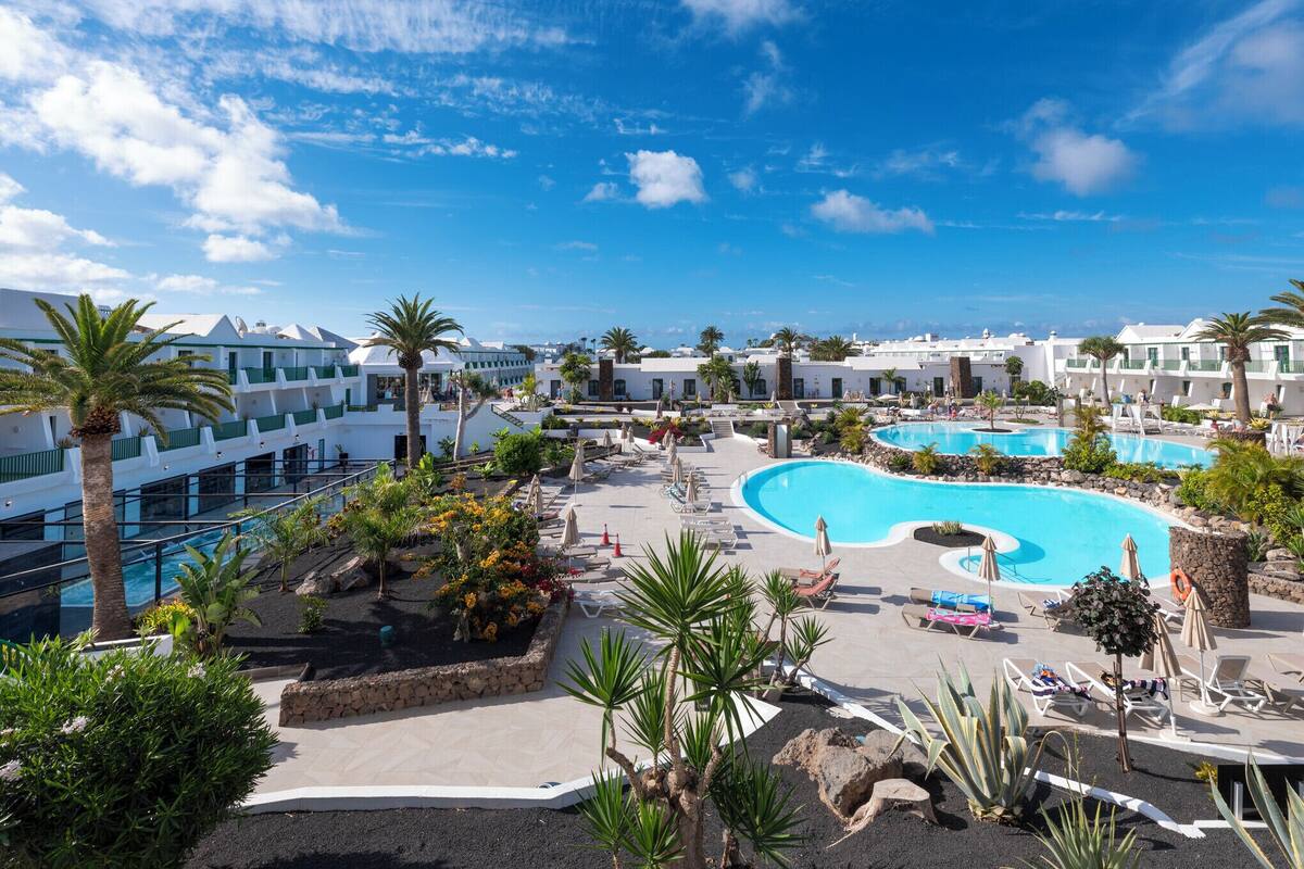 A resort with multiple swimming pools, palm trees, and a clear blue sky.