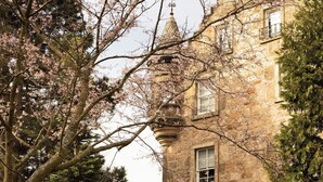 Un edificio de piedra con una torre, rodeado de árboles y césped.