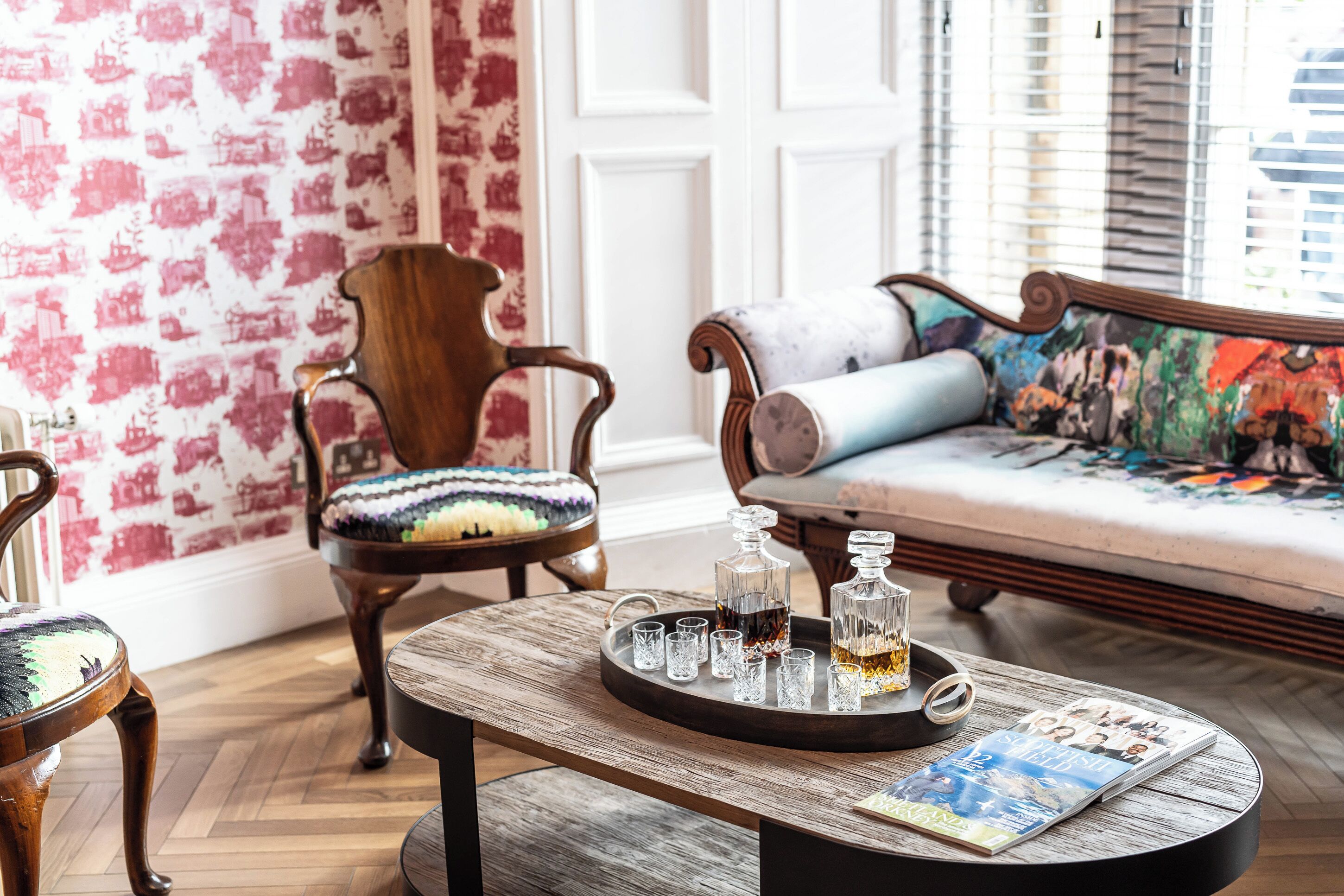 Une pièce comprenant une table basse en bois, un canapé agrémenté d’un coussin coloré et une chaise avec un coussin à motifs.