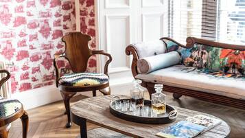 Une pièce comprenant une table basse en bois, un canapé agrémenté d’un coussin coloré et une chaise avec un coussin à motifs.