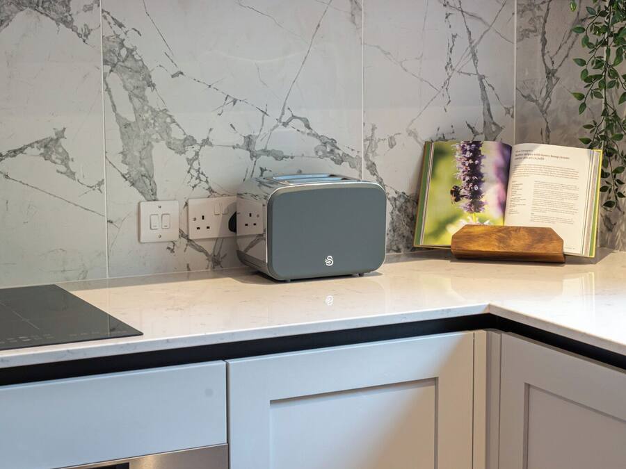 A kitchen with a marble backsplash, a built-in oven, and a countertop with a toaster.