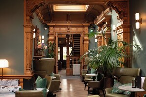 A lobby with ornate woodwork, a staircase, and seating areas. - The Scott (Edinburgh)