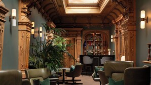 Una zona de bar con taburetes, una planta grande en maceta y decoración de pared ornamental.
