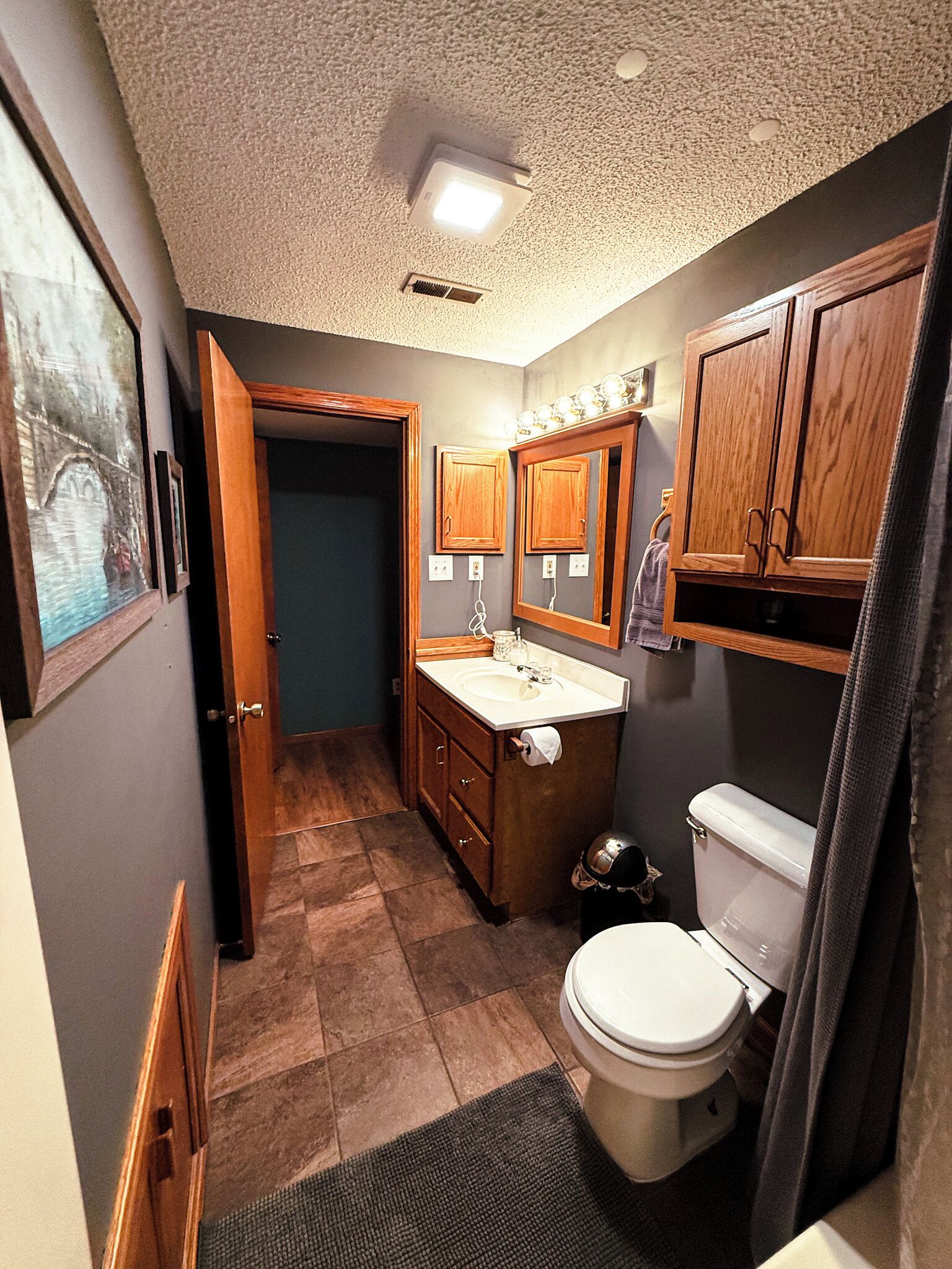 A compact bathroom with a toilet, sink, and wooden cabinets.