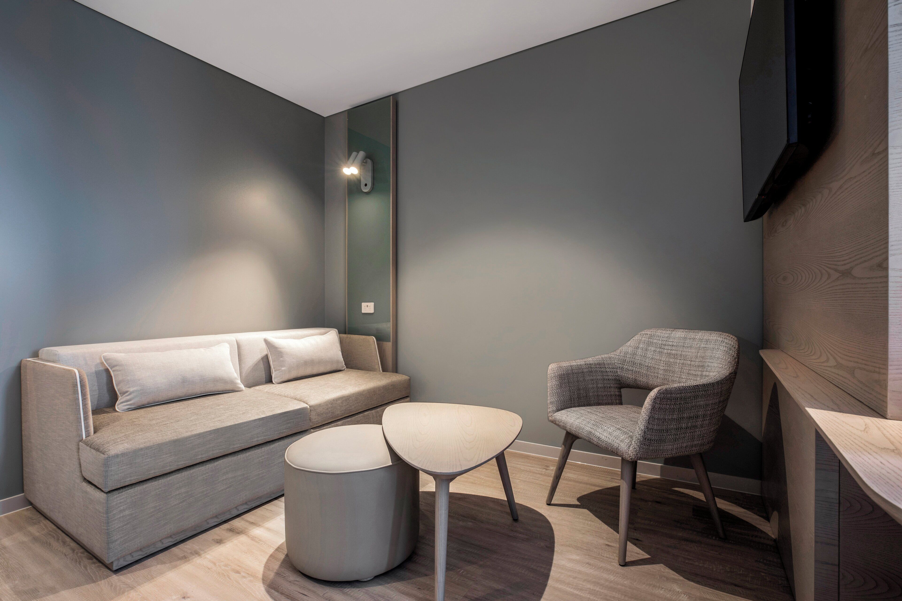 A modern living room with a sofa, a round ottoman, and a chair.