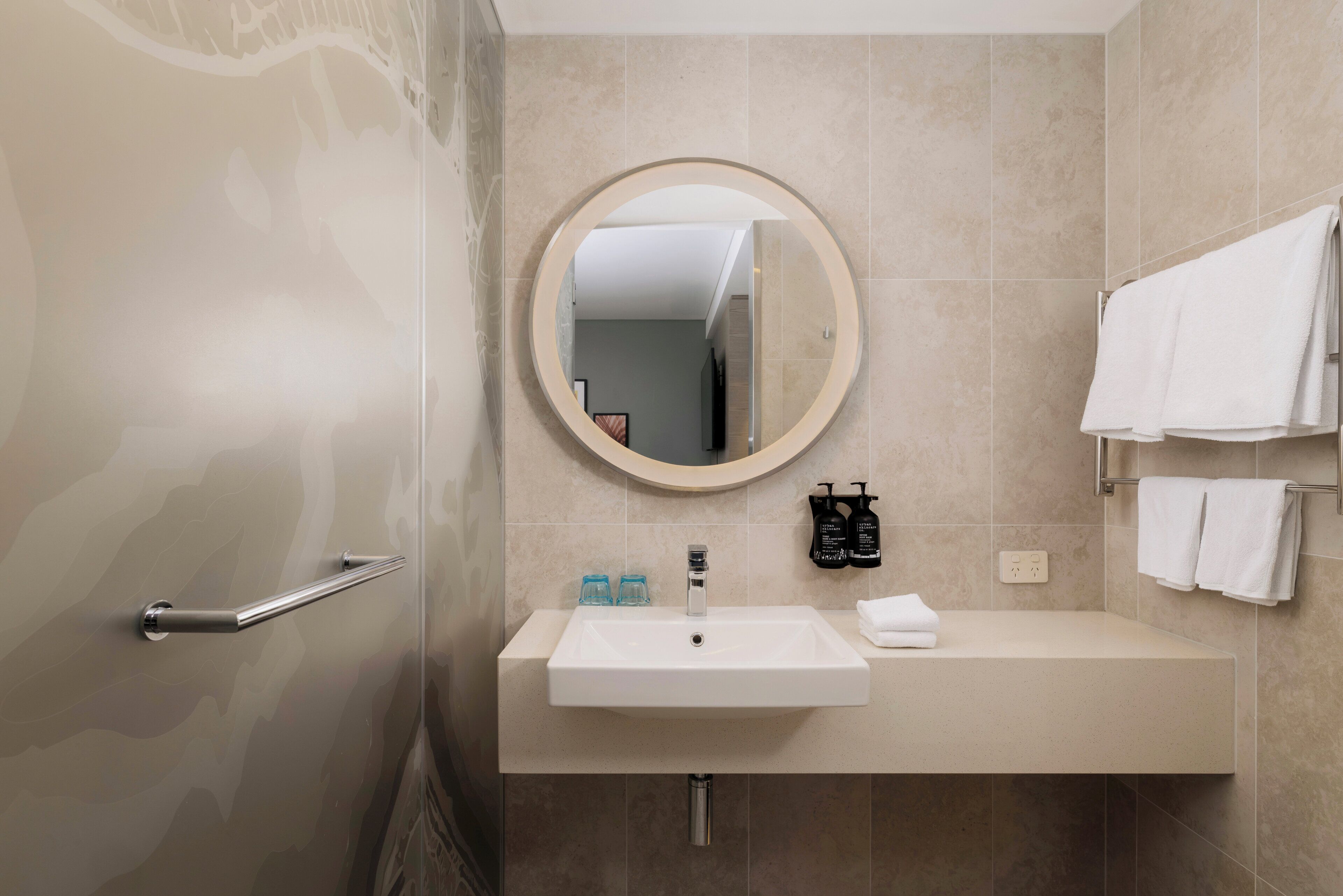 Une salle de bain équipée d’un lavabo, d’un miroir, d’un porte-serviettes et d’articles de toilette.
