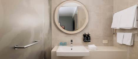 A bathroom with a sink, mirror, towel rack, and toiletries.