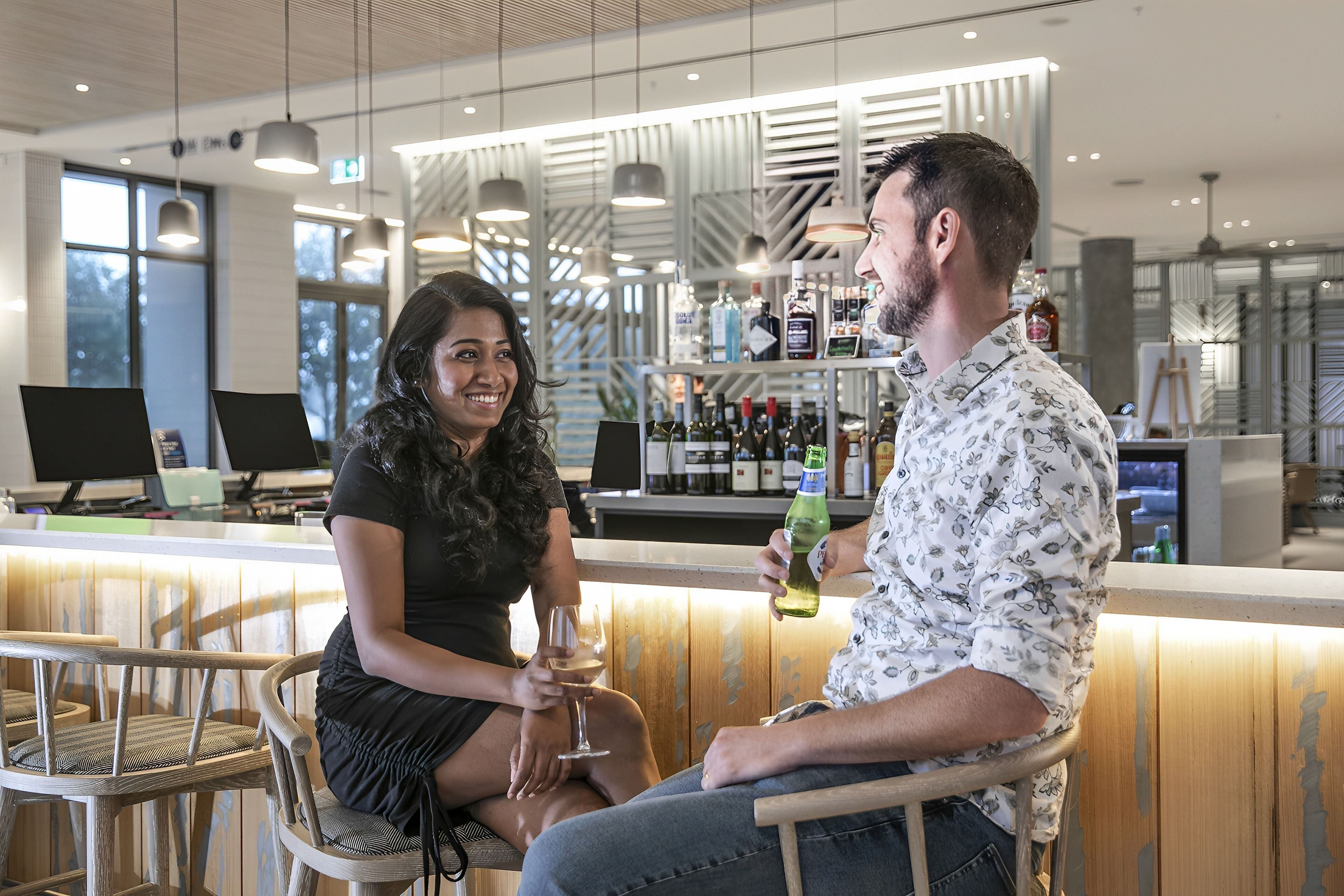 A bar area with wooden chairs, a counter with a wine bottle, and a modern interior design.
