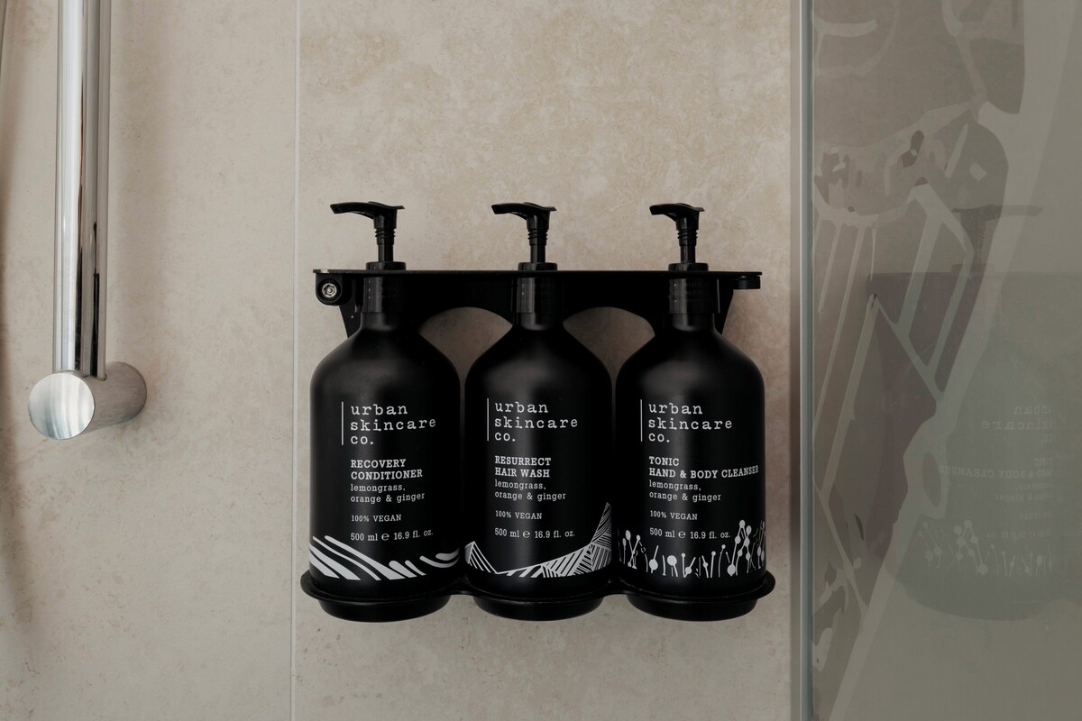 Tres botellas negras de productos Urban Skincare Co. sobre una pared.
