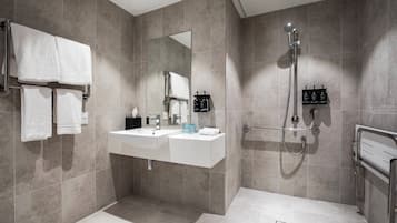 A modern bathroom with a sink, mirror, towel rack, and shower.
