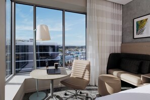 A modern hotel room with a large window, a round table, a cushioned chair, a sofa, and a lamp. - Holiday Inn & Suites Sunshine Coast by IHG (Maroochydore)