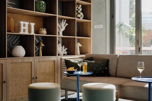 Una sala de estar moderna con un sofá, dos mesitas auxiliares y una estantería con adornos.