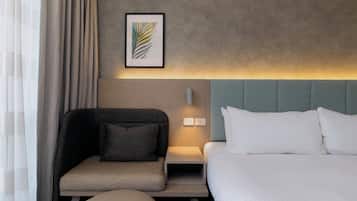 Una habitación de hotel con cama, sofá, una mesita y una lámpara fijada a la pared.