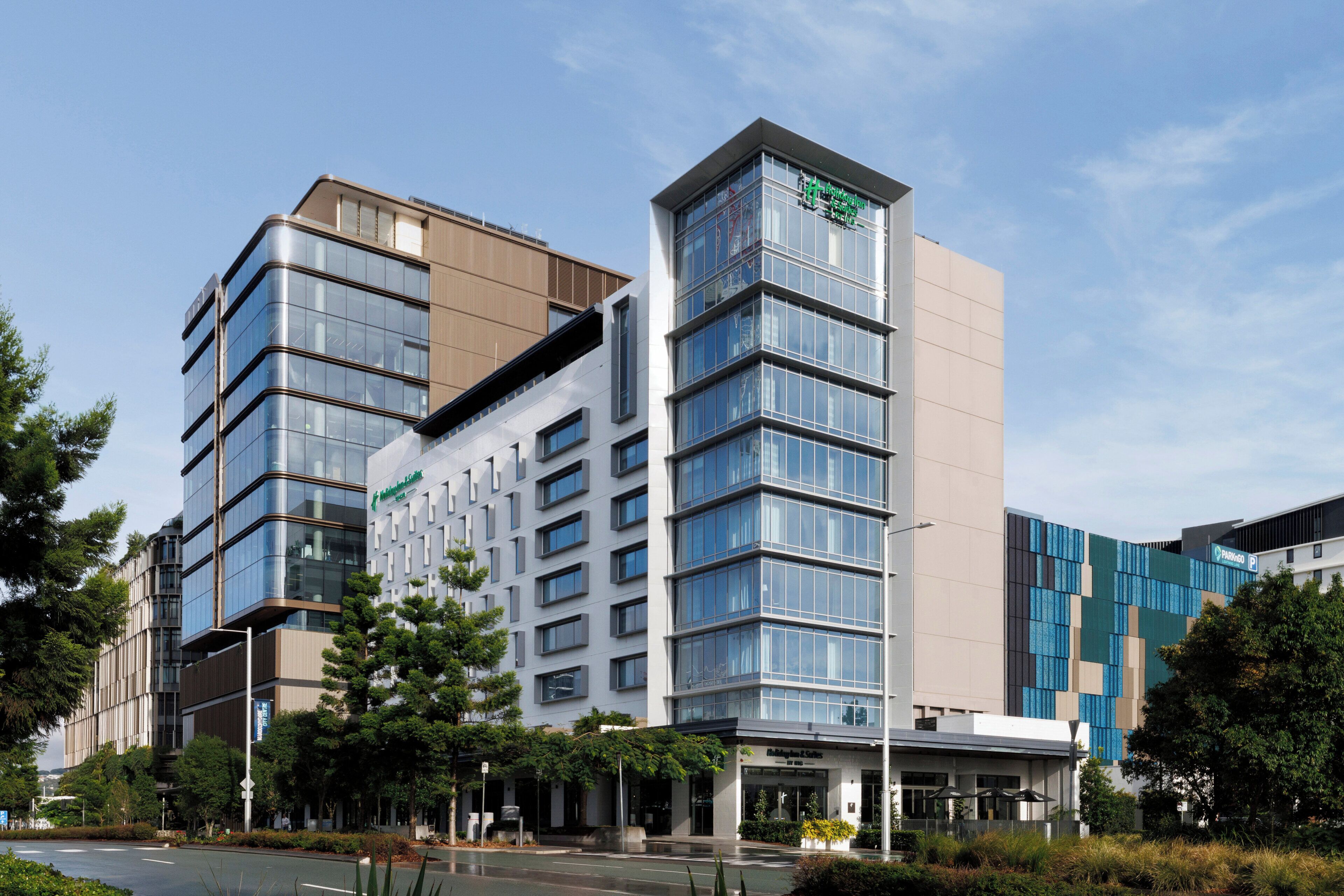 A modern hotel with multiple floors, large windows, and a visible restaurant on the ground floor.