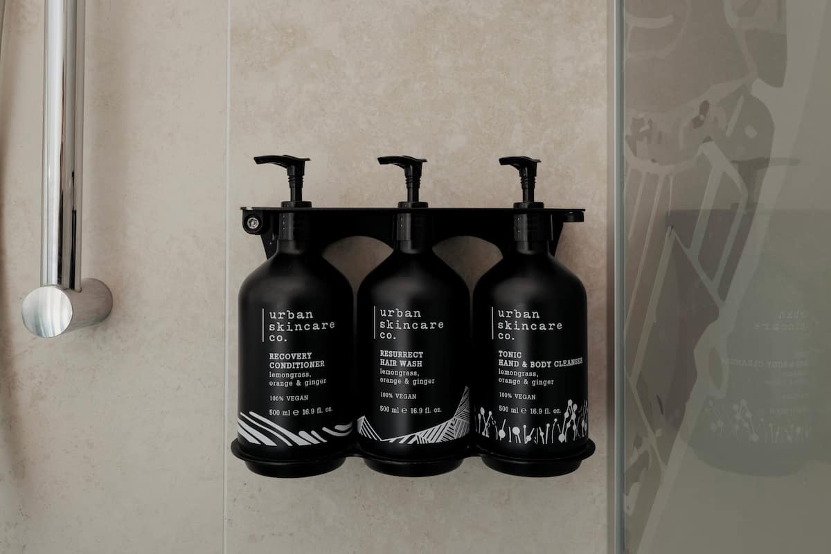 Kolme mustaa Urban Skincare Co. -tuotemerkkistä pulloa on asetettu seinälle.