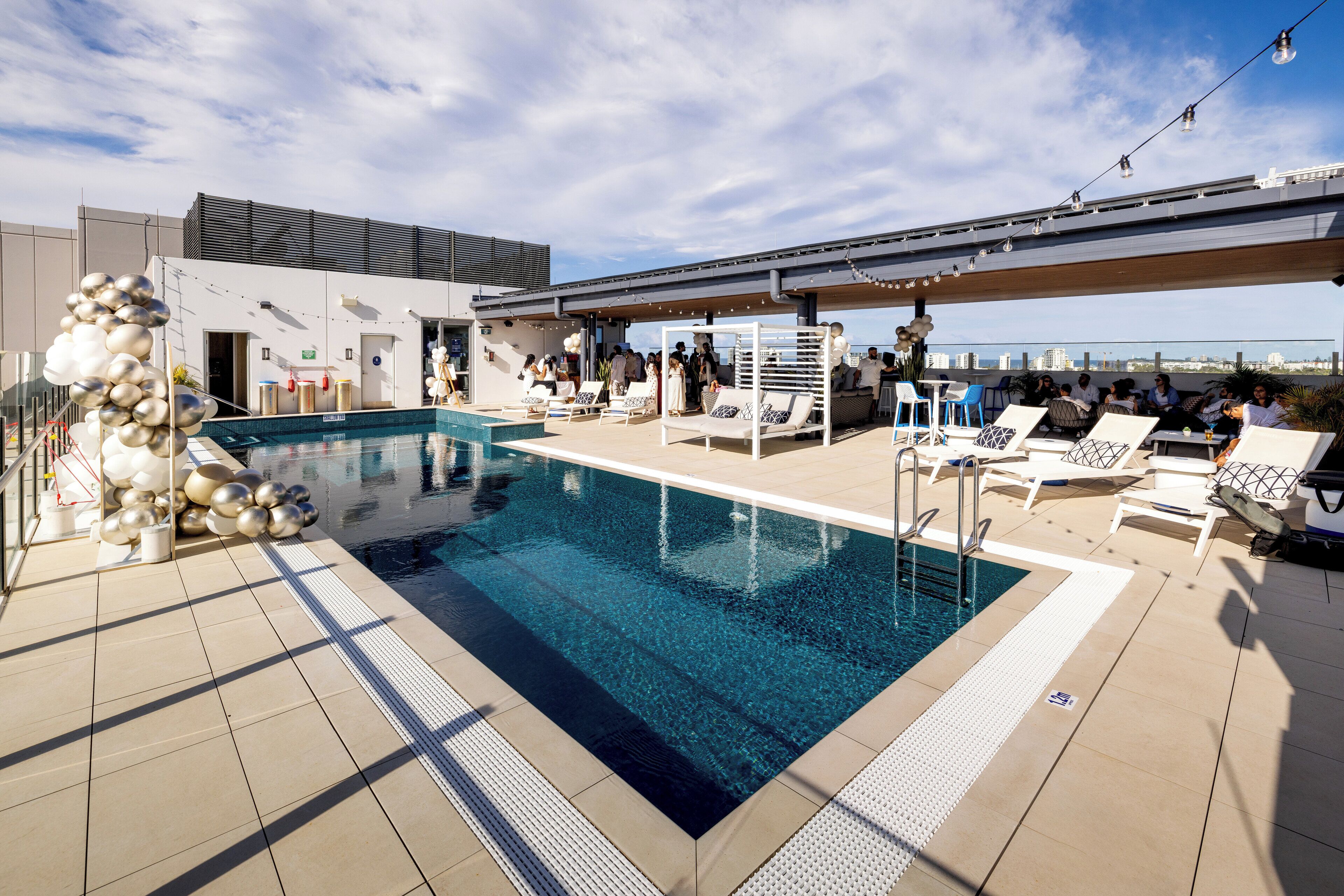 Et tagområde med pool, solstole og en overdækket siddeplads.
