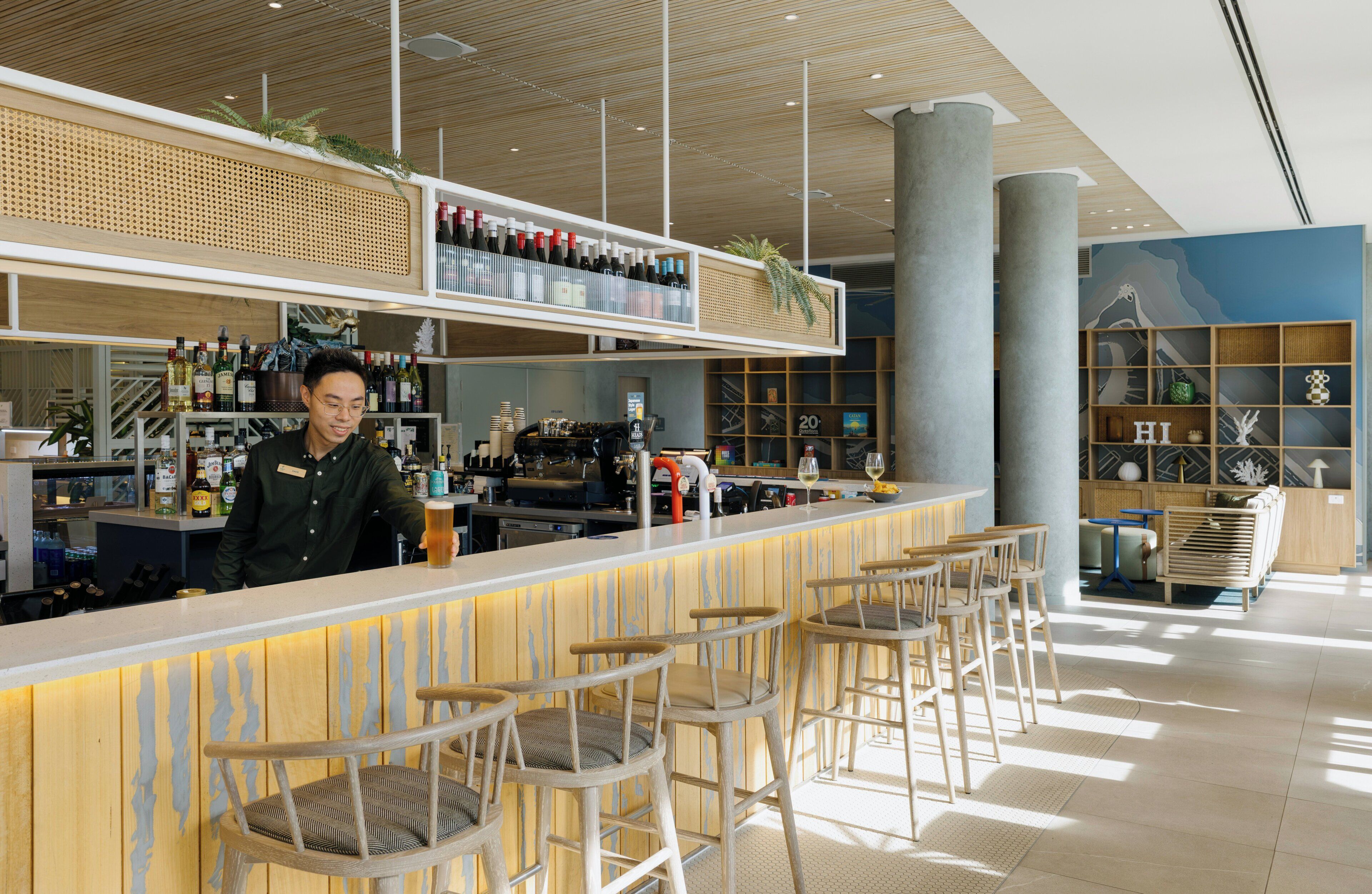 Una zona de bar con un cantinero, taburetes y estanterías llenas de botellas.