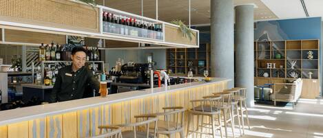 Una zona de bar con un cantinero, taburetes y estanterías llenas de botellas.