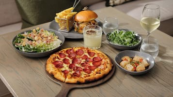 A table with a pizza, salad, burger, fries, and drinks.