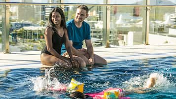 A couple sitting by a pool with a cityscape view.