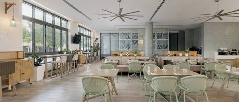 A spacious dining area with high ceilings, large windows, and modern furniture.