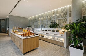 Un área de cocina moderna con una isla central, armarios de madera y una variedad de utensilios y electrodomésticos.