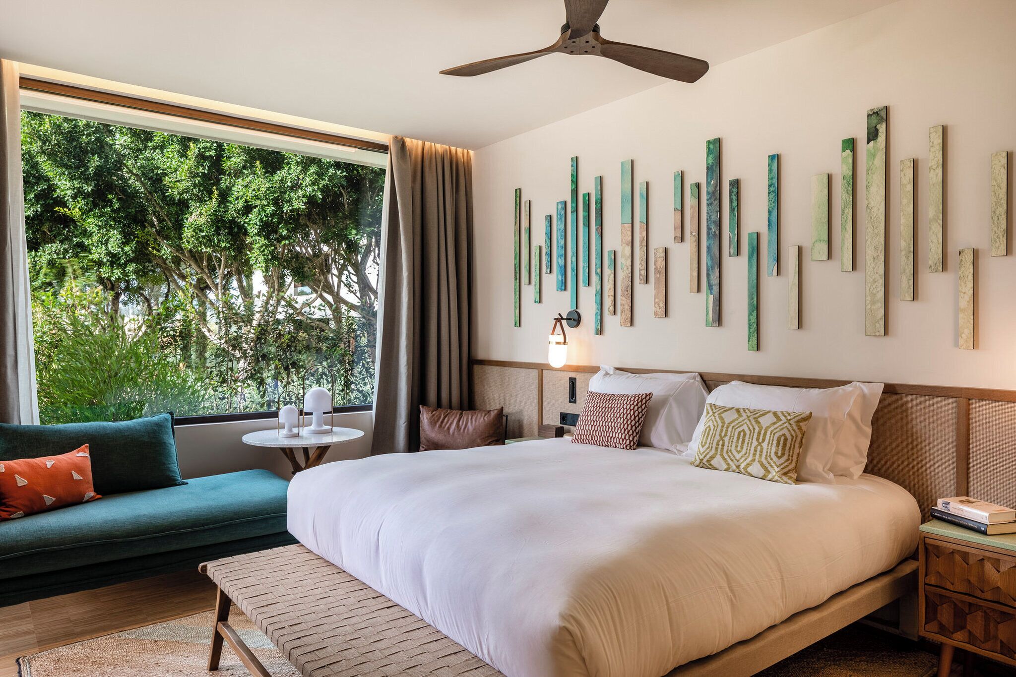 Une chambre d’hôtel avec un grand lit, un canapé, une petite table et un ventilateur de plafond.