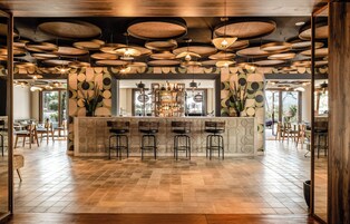 Una zona de bar con mostrador central, varios taburetes y una pared con diseño.