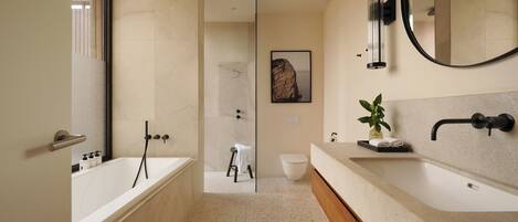 A modern bathroom with a bathtub, a shower, a sink, and a mirror.