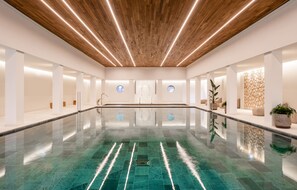 Swim laps in a sleek, modern pool area with a reflective floor and linear lighting.