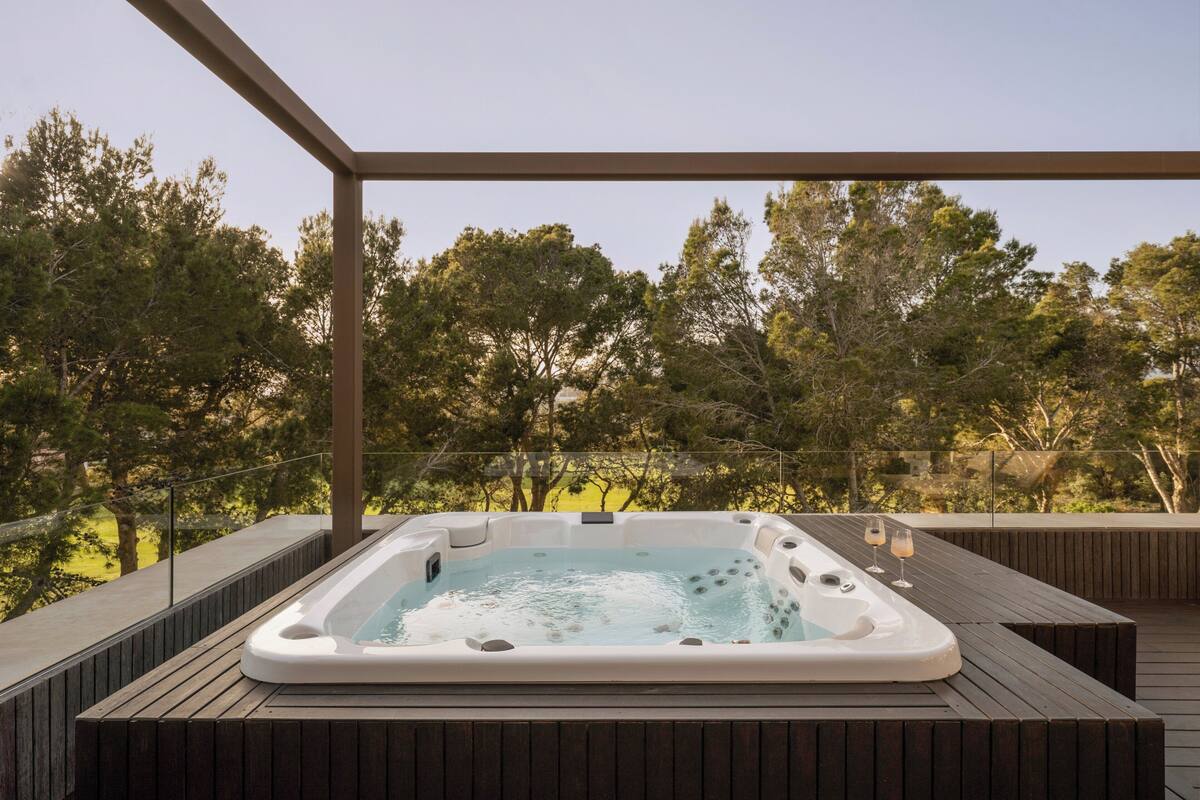 A hot tub on a wooden deck with a view of trees.