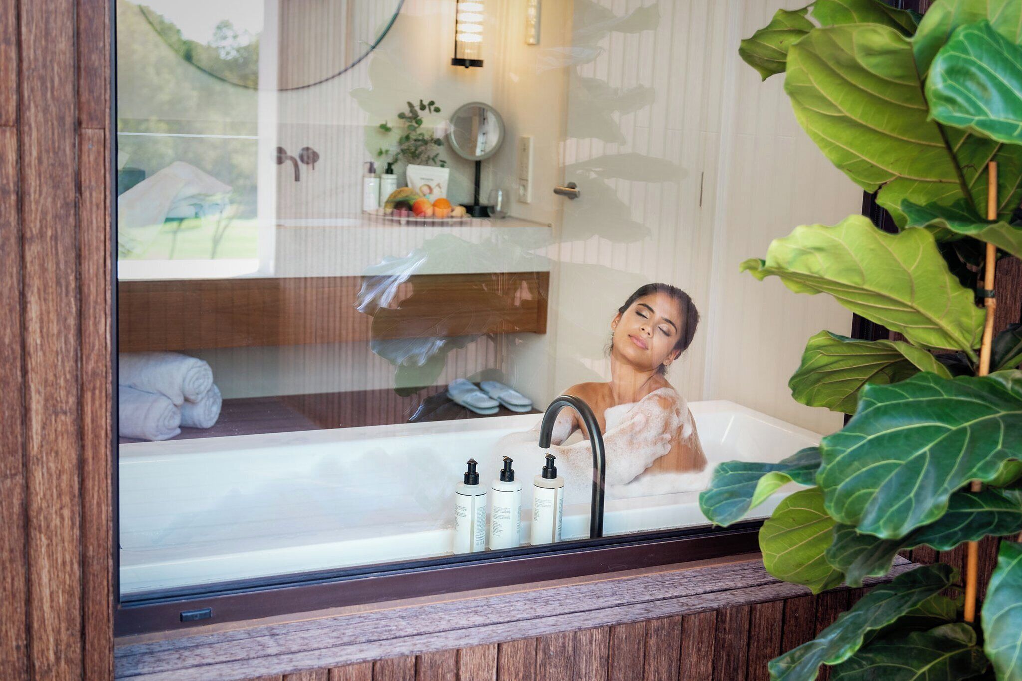 A bathroom with a bathtub, a mirror, and toiletries.