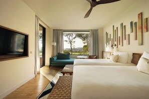 A hotel room with a large bed, a sofa, a TV, and a view of the outdoors. - Kimpton Aysla Mallorca by IHG (Calvia)