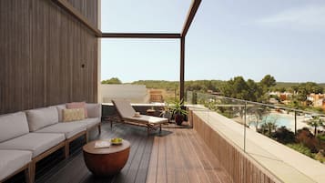 Una terraza de madera con sofá, sillones, una mesa redonda y plantas en macetas.