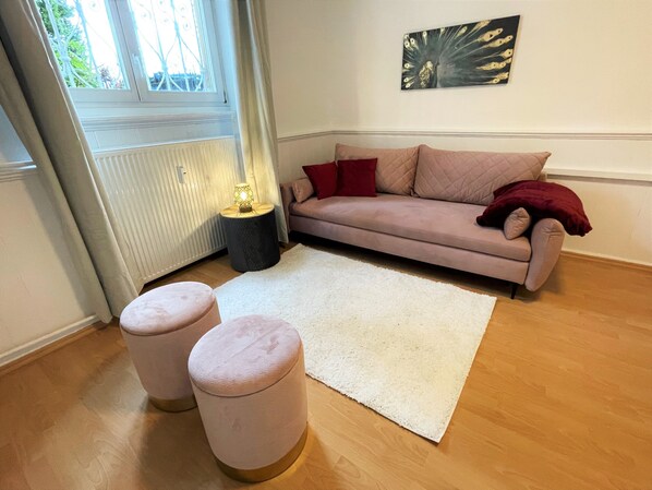 A living room with a beige sofa, two ottomans, a white rug, and a window with curtains. - ☆ Historic apartment in the gatehouse | kitchen | 75 m² (Wiesbaden)