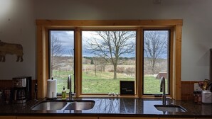 Een keuken met twee spoelbakken, een groot raam en uitzicht op het landschap.