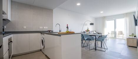 A modern kitchen with a central island, built-in appliances, and a dining area with a table and chairs.