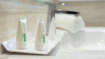 Dos botellas blancas con motivos de bambú verde sobre una bandeja blanca junto a un lavamanos.