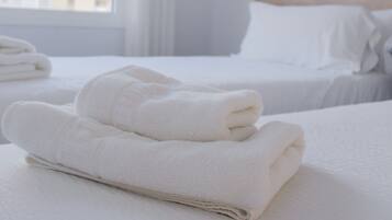 A hotel room with two beds, white linens, and a window with curtains.