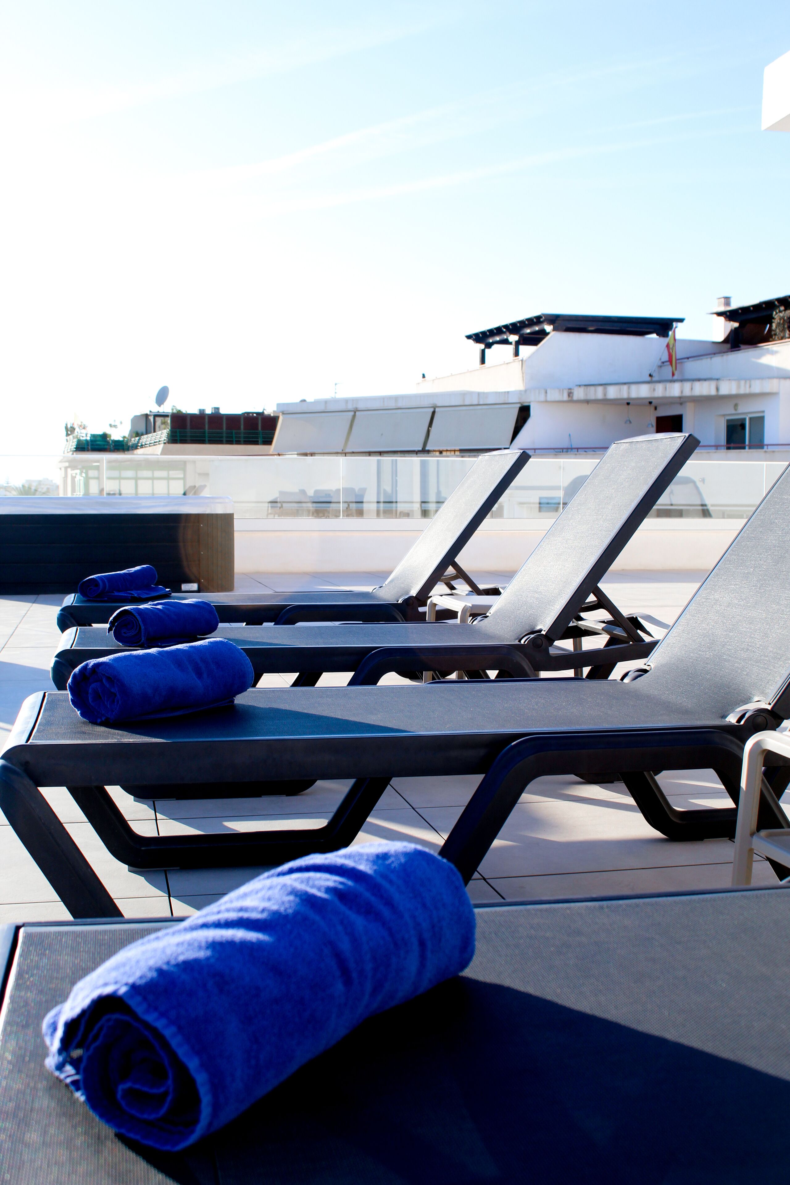A rooftop lounge area with sun loungers and rolled-up towels.