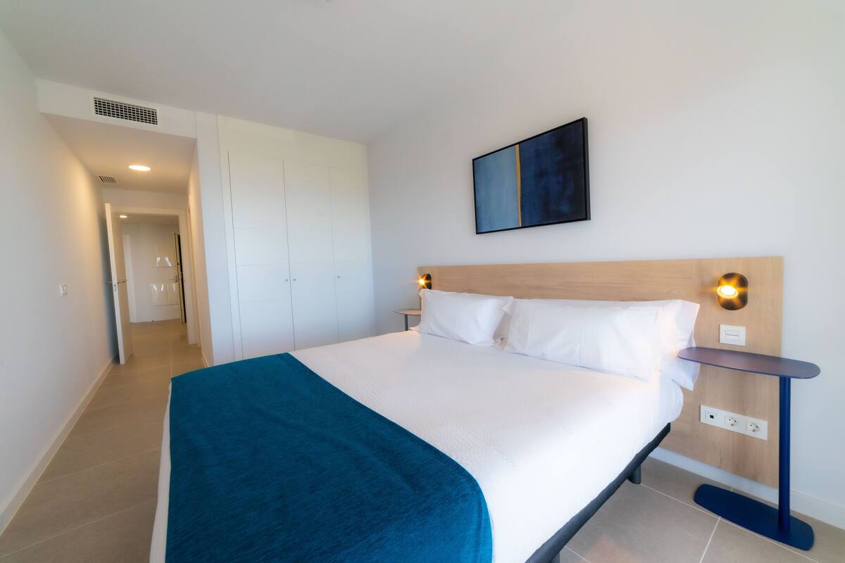 A neatly arranged hotel room with a bed, bedside table, and a wall-mounted artwork.