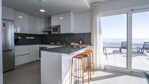Une cuisine moderne avec des meubles blancs, un îlot central et des tabourets de bar.