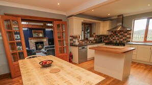 A kitchen with a wooden table, a stove, and cabinets. - Ridley Lodge (Morpeth)