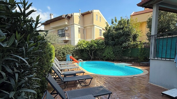 A pool area with lounge chairs and a wooden deck. - Arslan Villa (Marmaris)