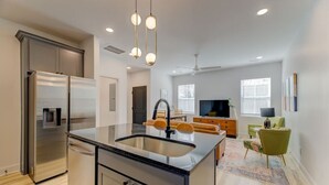A modern kitchen with a central island, stainless steel appliances, and pendant lighting. - Green House @ Township - Unit B | 3BR 3BA (Columbia)
