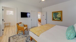 A bedroom with a bed, a chair, a television, and a painting on the wall. - Green House @ Township - Unit B | 3BR 3BA (Columbia)