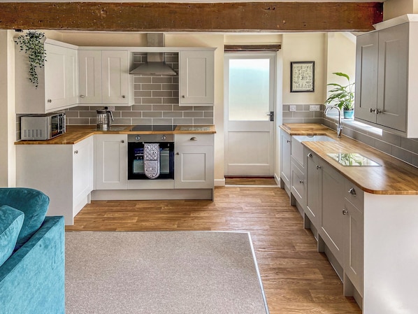 A compact kitchen with white cabinets, a built-in oven, and a microwave.