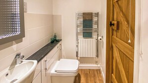 Un baño pequeño con lavamanos, inodoro y perchero para toallas.