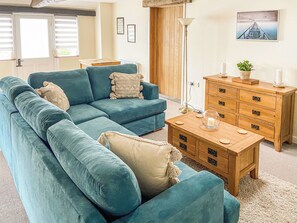 A living room with a sectional sofa, wooden dresser, and a lamp.