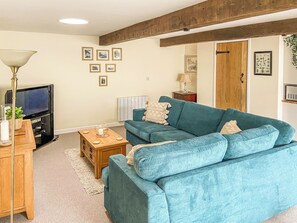 A living room with a blue sofa, a television, a wooden coffee table, and a lamp.